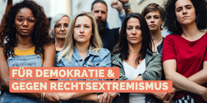 Gruppe von Menschen steht entschlossen Hand in Hand zusammen und schaut in die Kamera